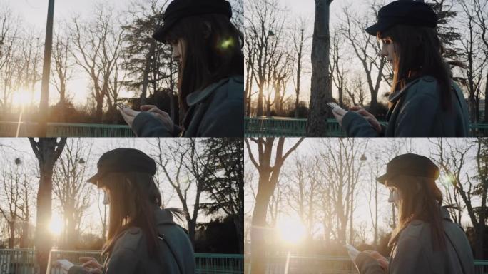 电影侧视图，美丽的女人沿着日落秋公园散步使用智能手机购物应用程序微笑慢动作。