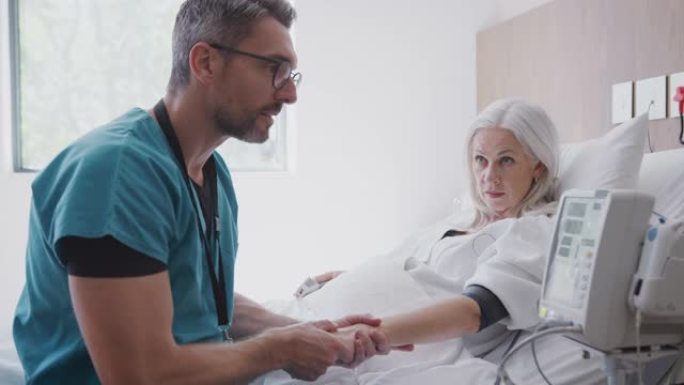 男护士用自动化机器在医院的病床上给成熟的女性病人血压