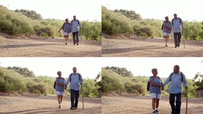 老年夫妇穿着背包一起在乡下徒步旅行