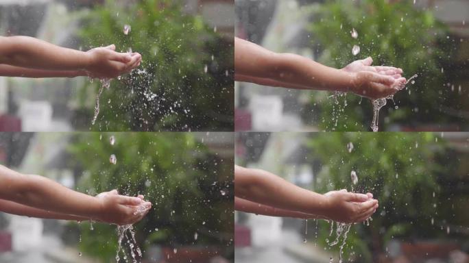 一个孩子的特写镜头把他的手放在雨中，你会看到滴在他的手上弹跳。