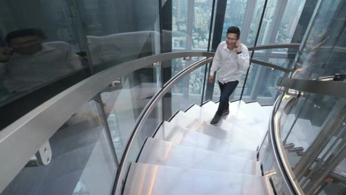 4k分辨率的亚洲商务男士，穿着休闲装，会说话的手机，走上楼梯