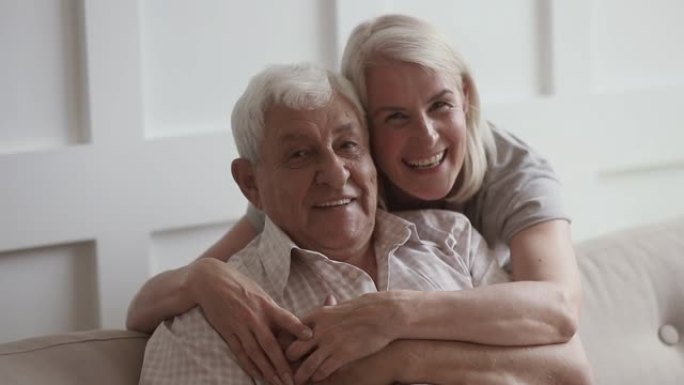 微笑的中年妇女拥抱80年代快乐的退休父亲。