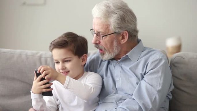 高级祖父和小孙子正在使用智能手机看手机
