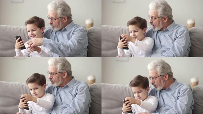 高级祖父和小孙子正在使用智能手机看手机