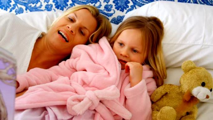 在舒适的家庭4k中，年轻的高加索母女在床上阅读故事书的前视图