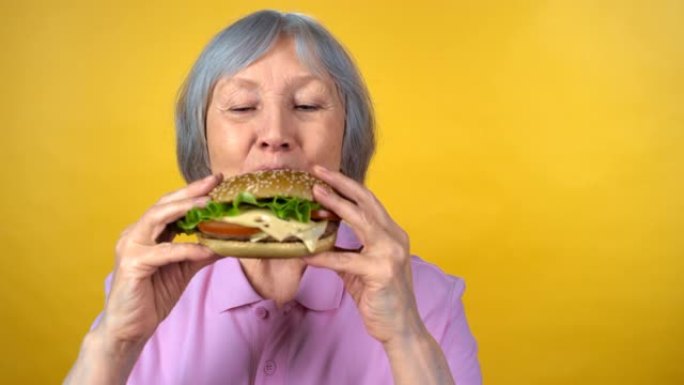 享受美味汉堡的老年妇女