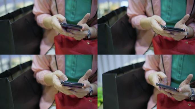 女人使用带有购物袋的智能手机，特写镜头