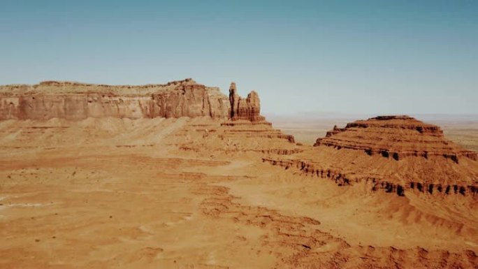无人机飞越阳光明媚的干燥沙漠，驶向美国国家公园保护区的大落基山脉和晴朗的蓝天。