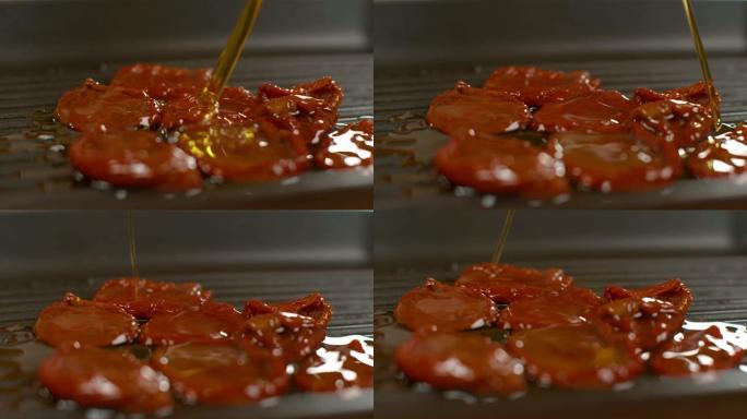 慢动作: 有机橄榄油溅到自家种植的晒干西红柿上。
