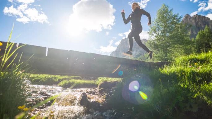 健康导向的年轻运动健身女子在绿色景观的山泉上跑过木桥