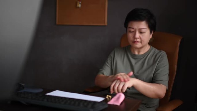 一名亚洲华裔女性下午在台式机前在手上涂护手霜