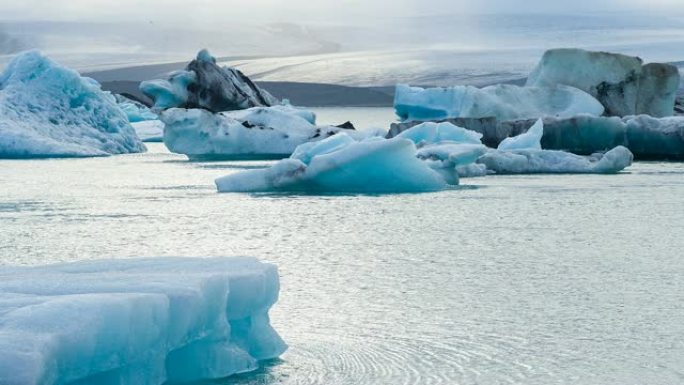 美丽的蓝色冰在冰岛的Jokulsarlon冰湖，背景是欧洲最大的冰川Vatnajokull