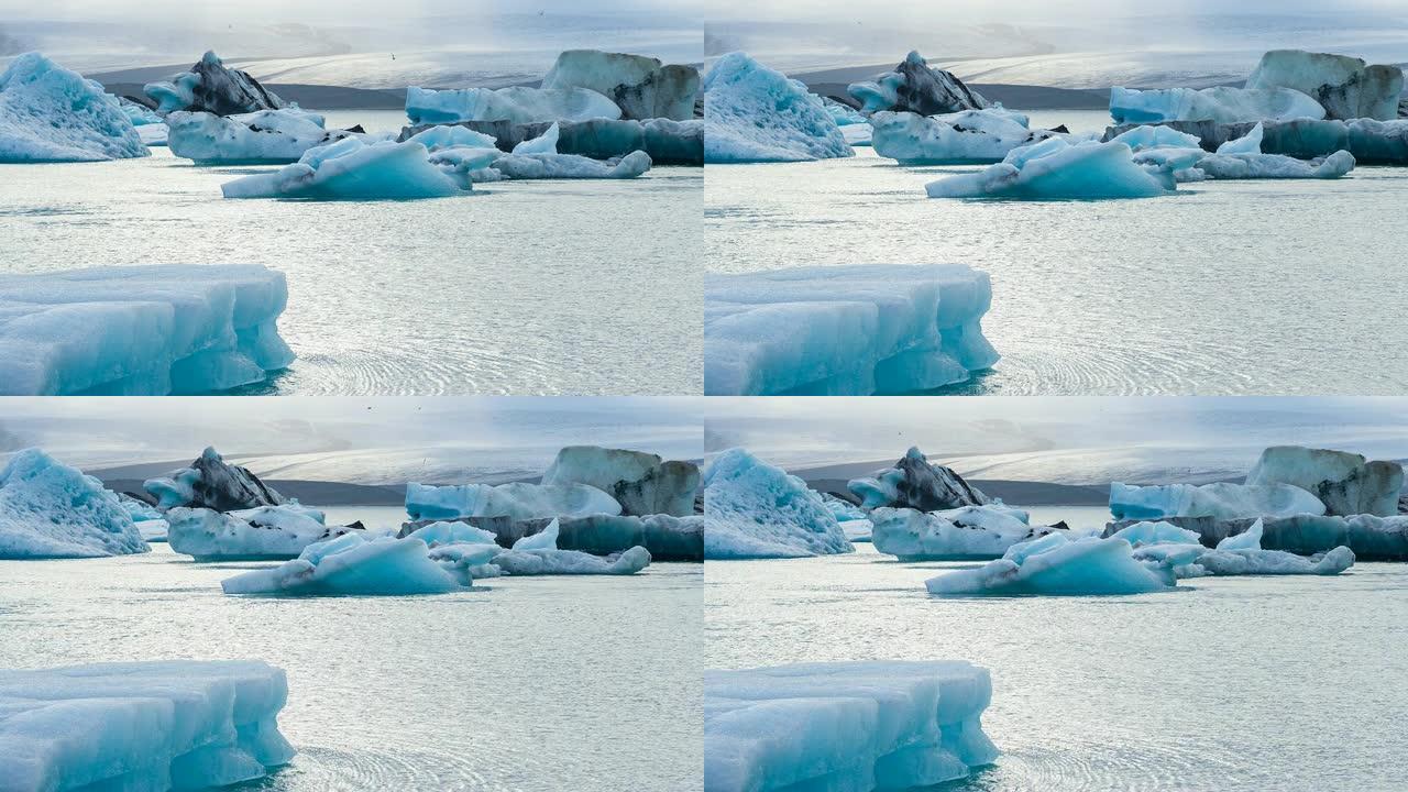 美丽的蓝色冰在冰岛的Jokulsarlon冰湖，背景是欧洲最大的冰川Vatnajokull