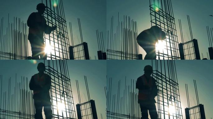 建筑工人在日落背景下与电枢一起工作。