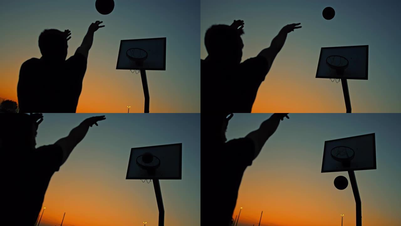MS超级慢动作剪影年轻人在黄昏时在室外篮球场上射击篮筐