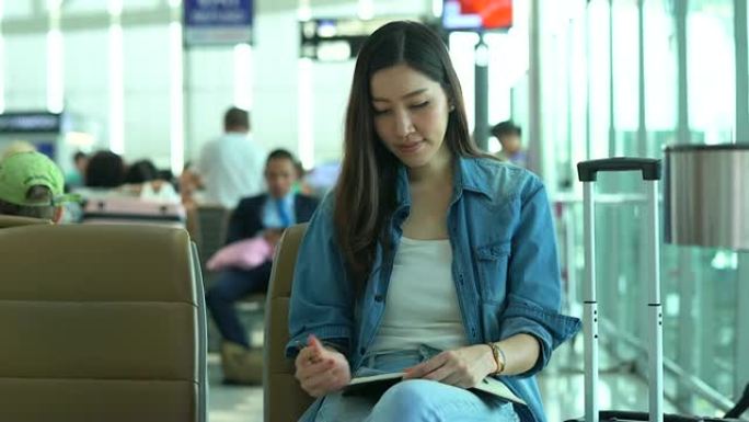 在航站楼机场的登机口等待和观看时间的年轻女性。年轻女性独自乘飞机旅行。