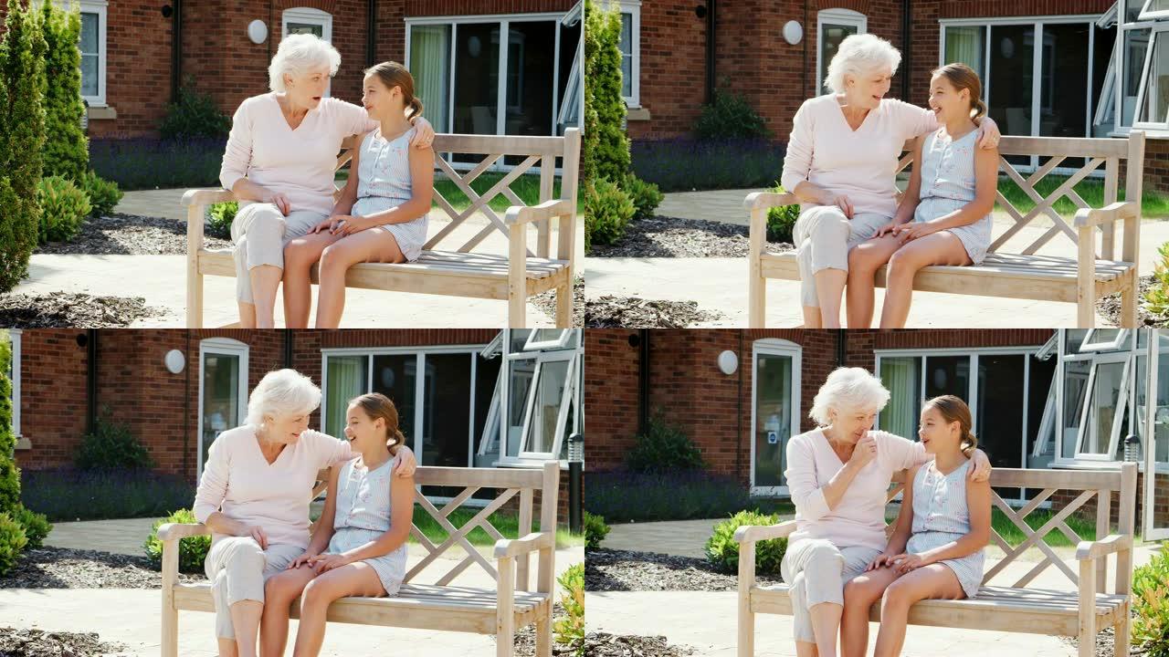 孙女在参观养老院时与祖母坐在长凳上