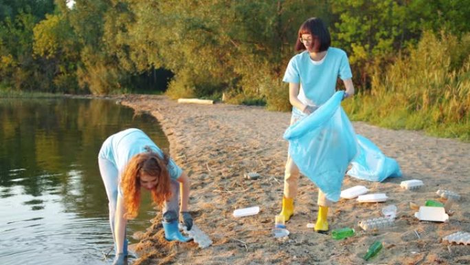 开朗的女孩志愿者在海滩上收集垃圾谈论清洁