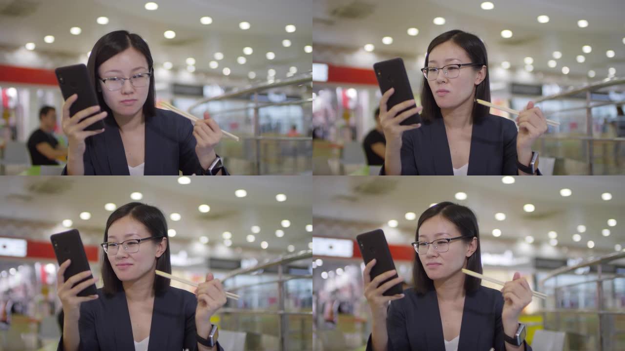 中国妇女在美食广场吃饭时检查智能手机