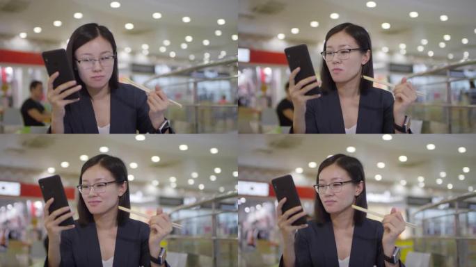 中国妇女在美食广场吃饭时检查智能手机