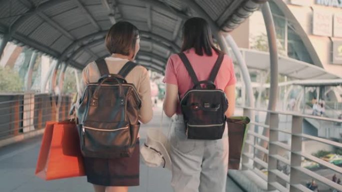 两名女游客提着购物袋走路慢动作