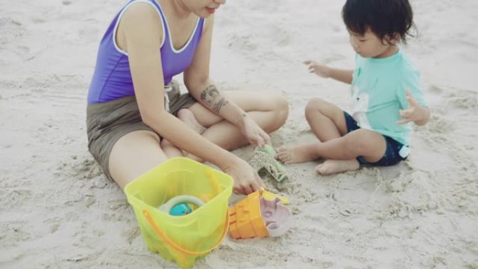 快乐男孩和母亲在沙滩上玩沙子和快乐