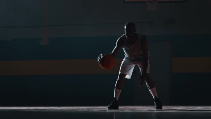 一名年轻的非洲职业男运动员的电影慢动作镜头正在健身房练习篮球运动