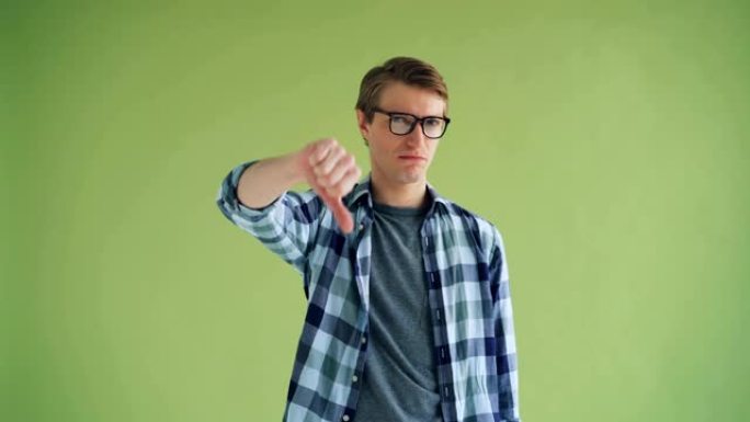 失望的年轻人的肖像显示出拇指朝下和摇头