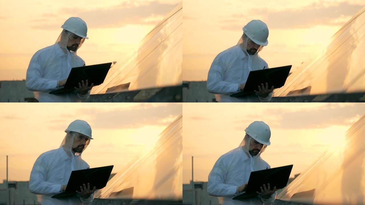 男工程师正在观察太阳能结构并使用笔记本电脑