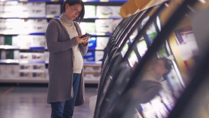 孕妇亚洲妇女在市场购物看电话