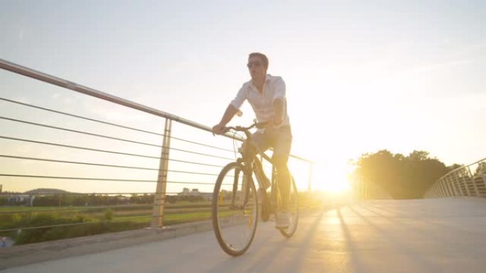低角度: 无忧无虑的家伙在阳光明媚的夏日早晨骑自行车时吹口哨。