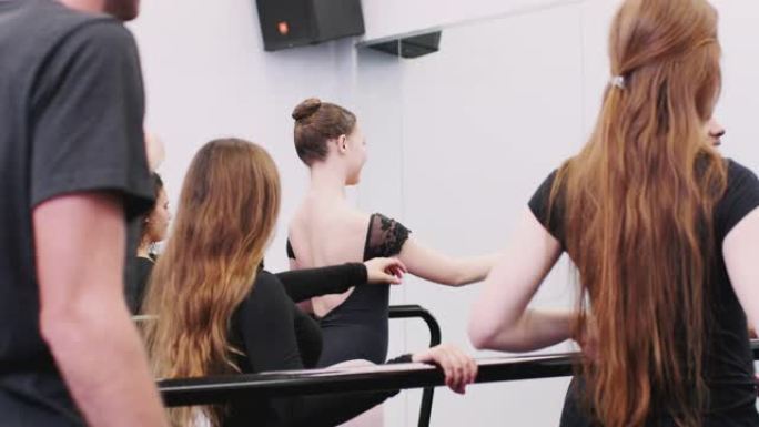 表演艺术学校的男女学生使用Barre在舞蹈工作室排练芭蕾舞