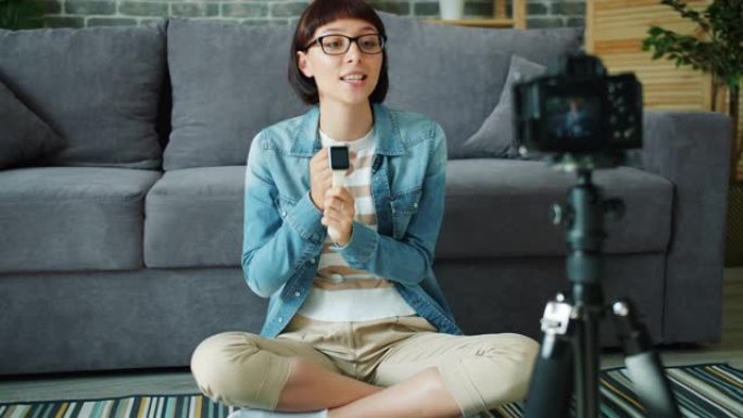 女性博客作者录制有关在公寓中使用相机的数字手表的视频