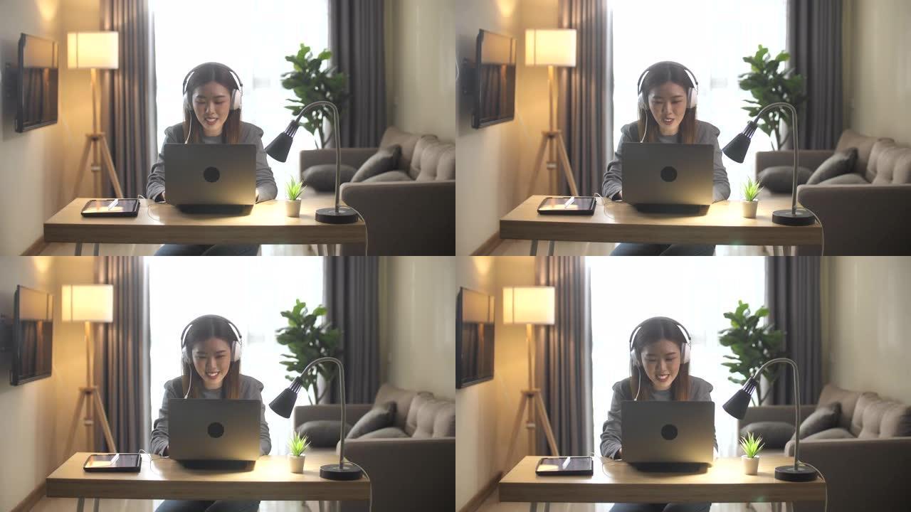 穿着休闲服装的亚洲女企业家在家里客厅使用笔记本电脑进行视频电话会议，并提供客户支持