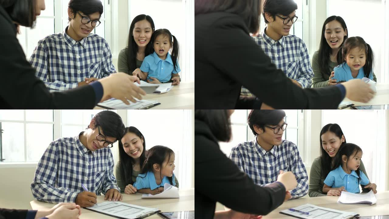 亚洲夫妇与女儿签署文件并握手新房房地产经纪人