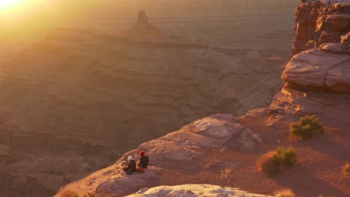 面目全非的人坐在悬崖边欣赏日落。美国犹他州死马点州立公园的万向镜头。UHD, 4K