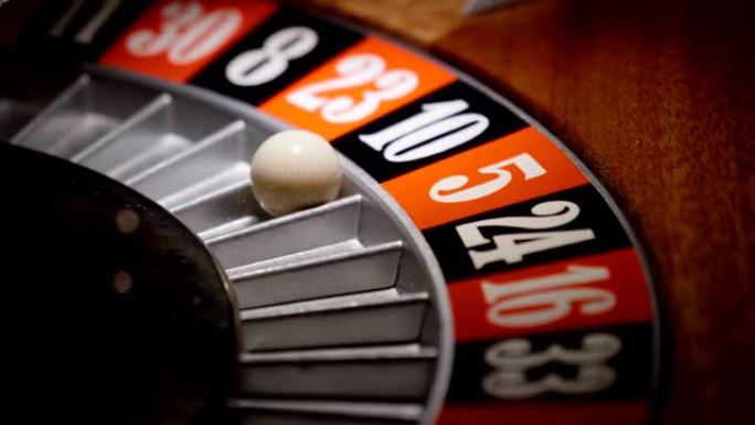 在赌场中轮盘赌的宏观拍摄，球进入绿色，红色或黑色数字。下注和下注的人可能赢得了丢失的徽章。