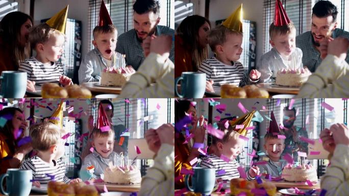 可爱的高加索男孩孩子在家庭聚会上吹生日蛋糕，爸爸对五彩纸屑爆炸慢动作感到惊讶。