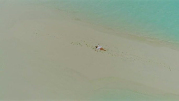 WS无忧无虑的女人躺在马尔代夫被海洋包围的田园诗般的热带海滩上