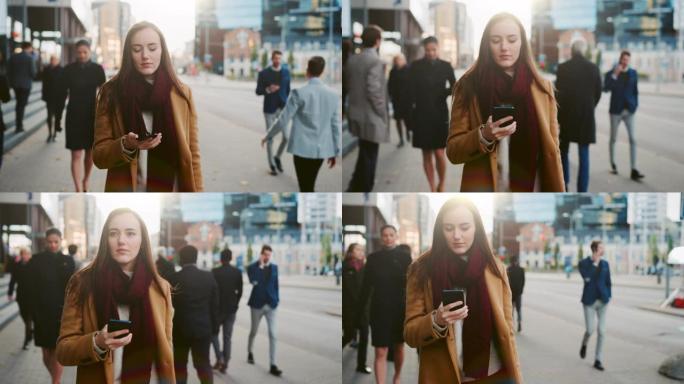 年轻聪明的衣着随意的女性在街上使用智能手机。商务人士和办公室经理在上班途中走通行证。她检查手机和走路