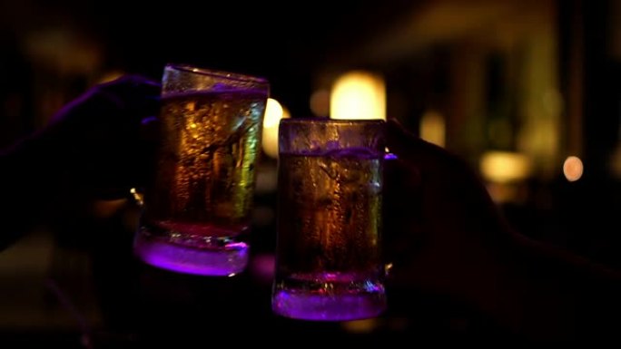 4k慢动作镜头烤啤酒和碰杯啤酒的特写镜头，在酒吧和餐厅一起欢呼，放松和喝酒的概念