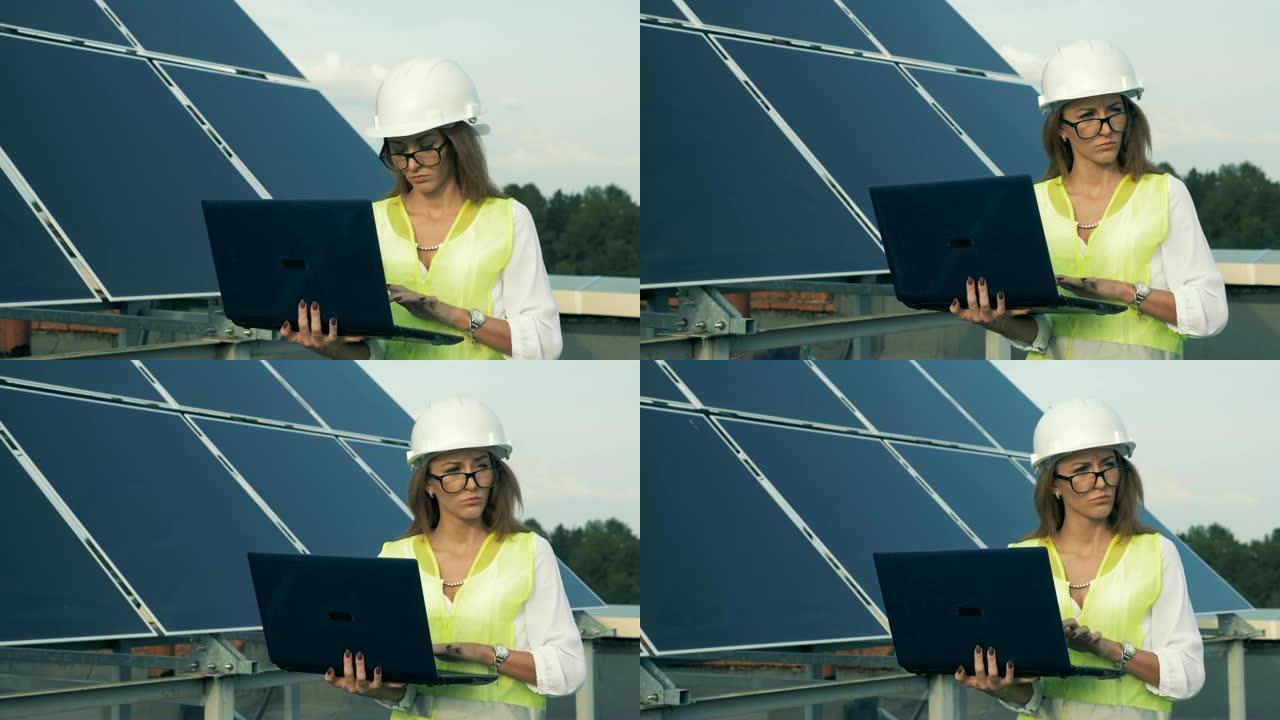 太阳能电池板和一名女工程师带着笔记本电脑一起走。替代能源概念。