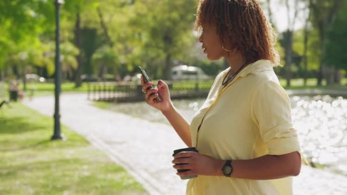 年轻女子正在用智能手机发短信时穿过公园