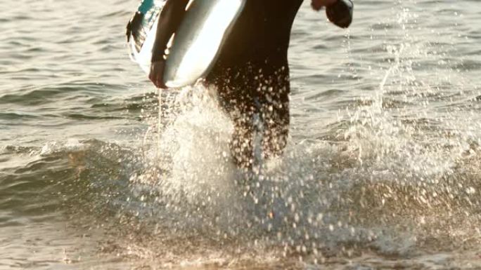 日落4k时，成年白人男性冲浪者在海上跑步的前视图
