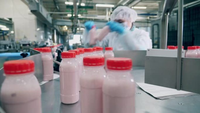 工厂工人从移动的生产线上挑选酸奶瓶。