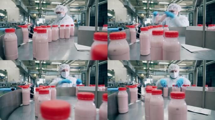 工厂工人从移动的生产线上挑选酸奶瓶。