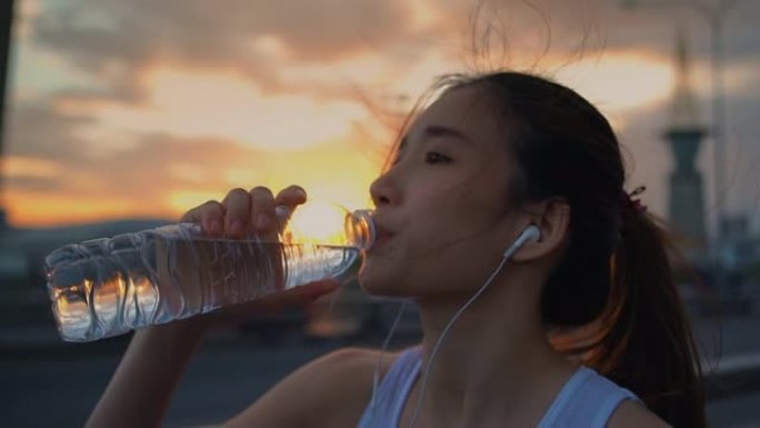 年轻的亚洲运动员女子跑步后喝水，特写镜头