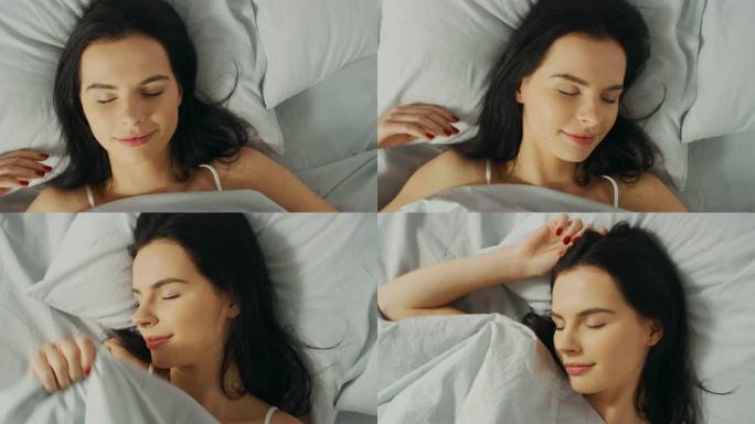 美丽的年轻黑发女人的肖像在清晨迷人地睡在她的床上。安静睡觉的女孩甜美温暖的景色。自上而下的旋转相机拍