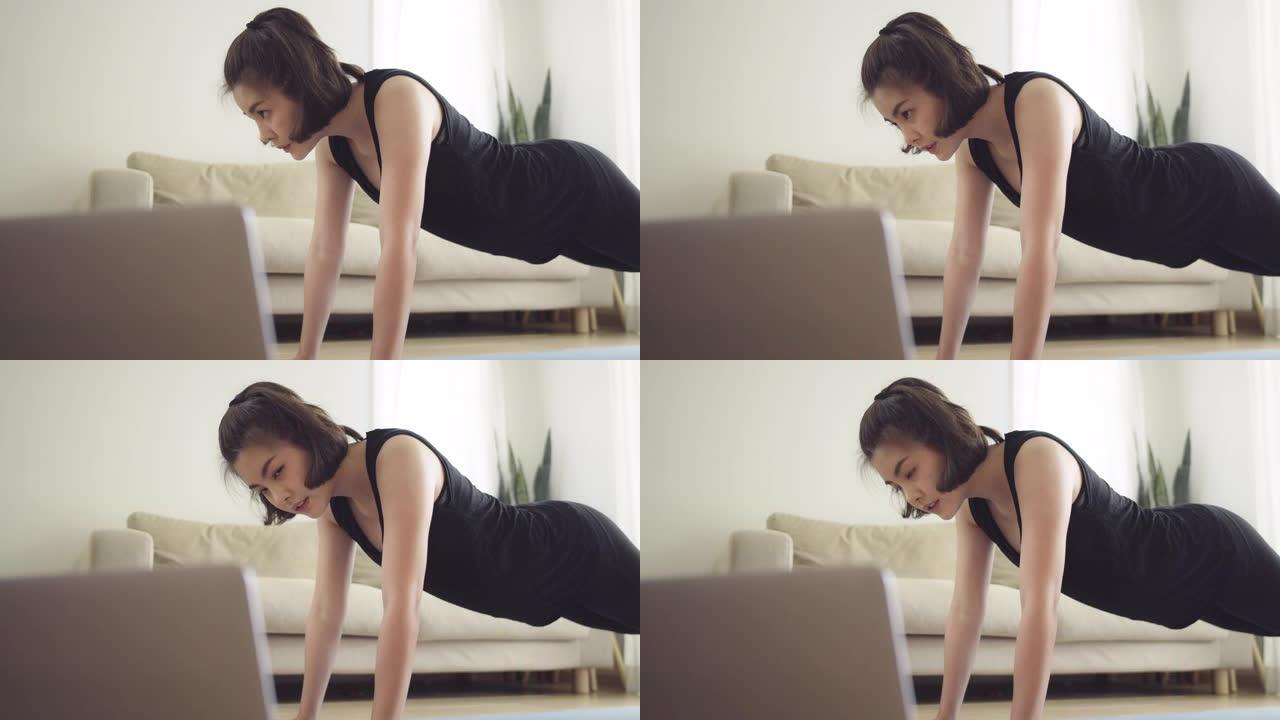 亚洲妇女在家中使用笔记本电脑锻炼