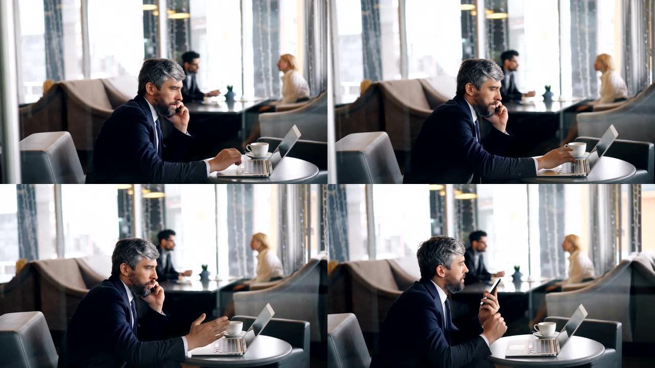 企业家在手机上聊天并在咖啡馆使用笔记本电脑